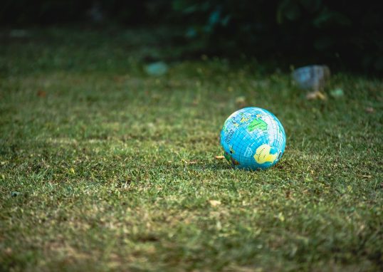 blue and white desk globe on green grass field during daytime