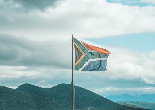 a flag on a pole with mountains in the background