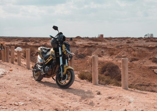 a motorcycle parked on the side of a dirt road